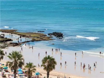 a group of people on a beach with the ocean at Fantastic Apartments 1 Bedroom in Olhos de Água