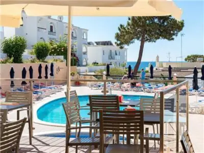 a table with chairs and an umbrella next to a pool at Fantastic Apartments 1 Bedroom in Olhos de Água