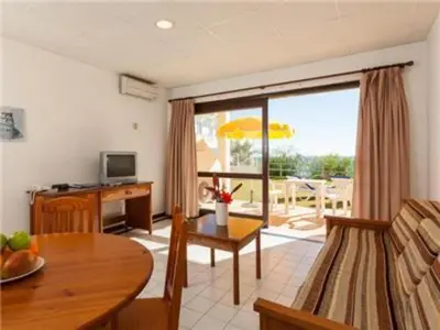 a living room with a table and a room with a patio at Fantastic Apartments 1 Bedroom in Olhos de Água