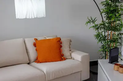 an orange pillow on a white couch in a living room at Sun & salt Apartment in Albufeira
