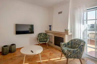 a living room with a fireplace and two chairs and a table at Summer Villa in Albufeira