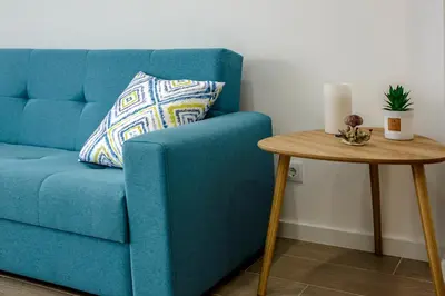 a blue couch with a pillow next to a table at Apartment Sandi in Albufeira