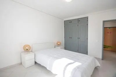 a white bedroom with a white bed and two lamps at La vie simple appartement in Albufeira