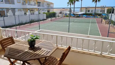 a table and chairs on a balcony with a tennis court at Casa ARRIFES in Albufeira