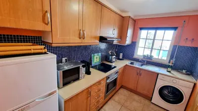 a kitchen with wooden cabinets and a washer and dryer at Casa ARRIFES in Albufeira