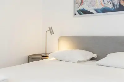 two beds with white pillows sitting next to a lamp at TAC - Bliss Vilamoura in Quarteira