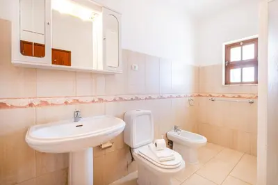 a white bathroom with a sink and a toilet at Villa Brid in Albufeira