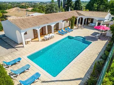an image of a swimming pool with chairs and a house at Villa Brid in Albufeira