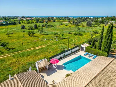 a house with a swimming pool and an umbrella at Villa Brid in Albufeira