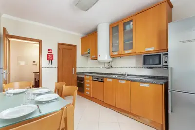 a kitchen with wooden cabinets and a table and a refrigerator at Blife RYA private rooms - Airport stay in Faro
