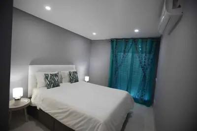 a bedroom with a white bed and a blue window at Atlantic Pearl by the Sea - Quarteira in Quarteira