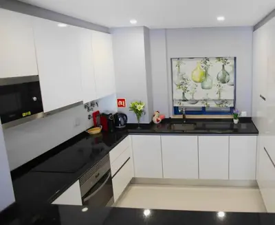 a kitchen with white cabinets and a black counter top at Atlantic Pearl by the Sea - Quarteira in Quarteira