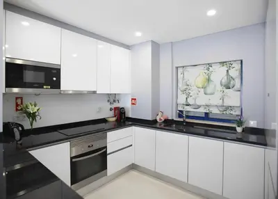 a kitchen with white cabinets and black counter tops at Atlantic Pearl by the Sea - Quarteira in Quarteira