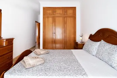 a bedroom with a large bed and a wooden cabinet at Villa Magdalena in Albufeira