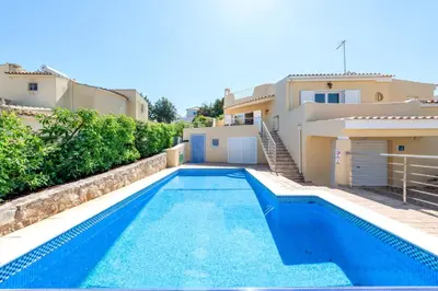 a swimming pool in front of a house at Villa Pinheiro in Albufeira