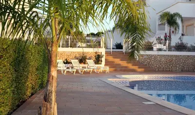 a palm tree sitting next to a swimming pool at Rui's Studio - Farmvillage - Free Wifi in Albufeira