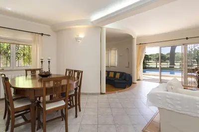 a dining room and living room with a table and chairs at Vila Caraibas - Vilamoura - by HDproperties in Vilamoura