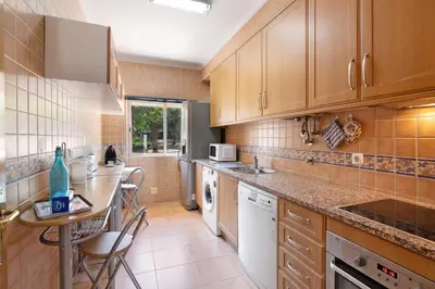 a kitchen with wooden cabinets and a table in it at Casa da Saudade no centro de Faro in Faro