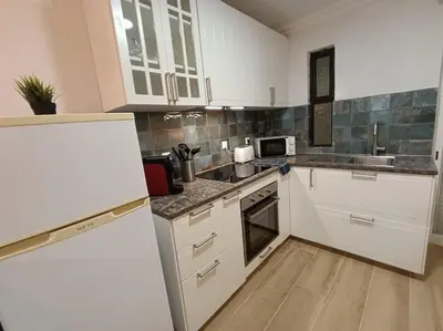 a kitchen with white cabinets and a wooden floor at Albufeira - Sun, Pool and Marina View! in Albufeira