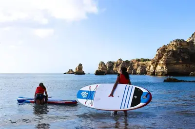 two people in the water with surfboards in the ocean at Maison avec piscine et jacuzzi in Guia