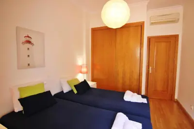 a bedroom with two beds and a wooden door at Los Arcos 3 - Pool & Vilamoura Center in Vilamoura