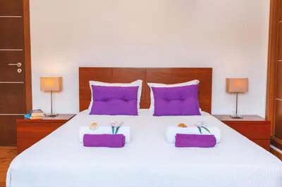 a bedroom with a large white bed with purple pillows at Villa Maya Bay by Algarve Vacation in Guia