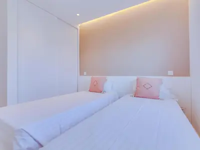 two beds in a room with white walls and pink pillows at AL - Apartamento Novo Horizonte in Vilamoura