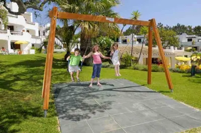 three children playing on a trampoline in a yard at Balaia Golf Village apt 105 in Albufeira