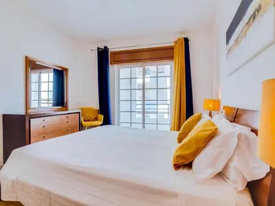 a bedroom with a large white bed with a window at Central 2bdr apartment in Quarteira in Quarteira