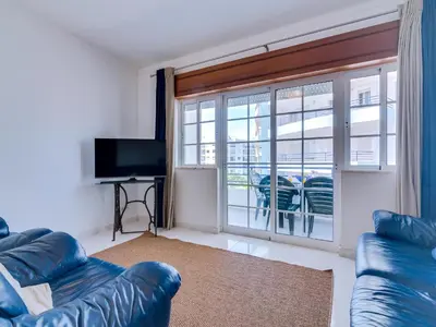 a living room with a couch and a large window at Central 2bdr apartment in Quarteira in Quarteira