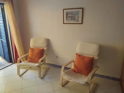 two chairs with orange pillows sitting in a room at SolNascenteII-Vilamoura in Quarteira