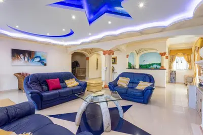 a living room with two blue couches and a glass table at Exceptional Villa with Pool, Tennis Court, Games Room in Quarteira