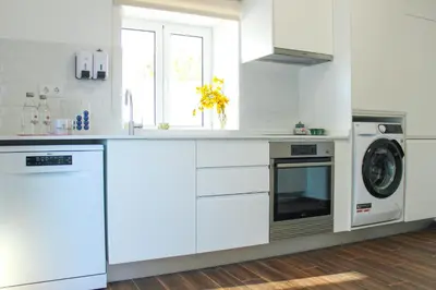 a kitchen with white cabinets and a washer and dryer at Monte do Couto in Albufeira