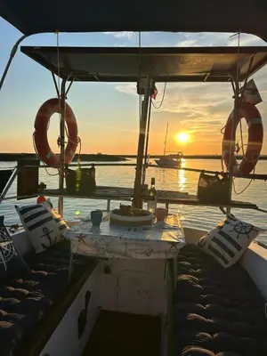 a boat with a table and a sunset on the water at Houseboat - Faro in Ria Formosa in Faro
