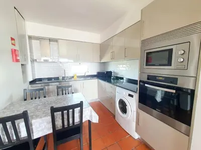 a kitchen with a table and a washer and dryer at Apartamento do Moinho acesso à Piscina in Albufeira