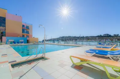 a swimming pool with two chairs next to a building at Marina de Albufeira by Garvetur in Albufeira
