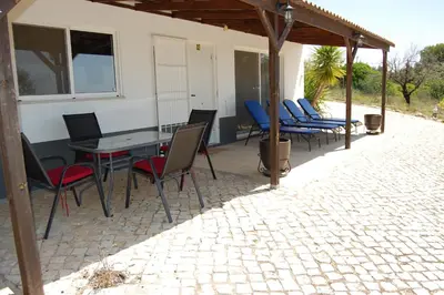 a patio with chairs and a table and a building at Charmante Villa mit 3 Schlafzimmer und Blick zum Meer in Santa Bárbara de Nexe