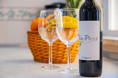 a bottle of wine and two wine glasses on a counter at Cosy apartment in Jardins Vale de Parra in Guia