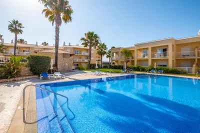 a large swimming pool in front of a building with palm trees at Cosy apartment in Jardins Vale de Parra in Guia