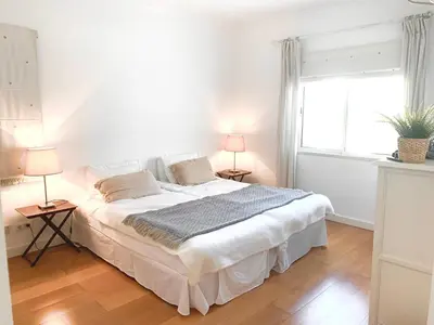 a white bedroom with a large bed and a window at Sandnblue - Encosta Do Lago Resort Club - Quinta do lago near Beach & lake BEST LOCATION in Quinta do Lago