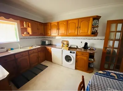 a kitchen with wooden cabinets and a washing machine at Moradia VSSG em Vilamoura in Quarteira