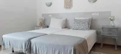 two beds in a bedroom with white walls at Galé Garden House in Guia