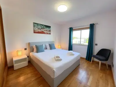 a bedroom with a bed and a chair and a window at Fantastic Villa, Private Pool, BBQ, AC and Wi-Fi in Quarteira