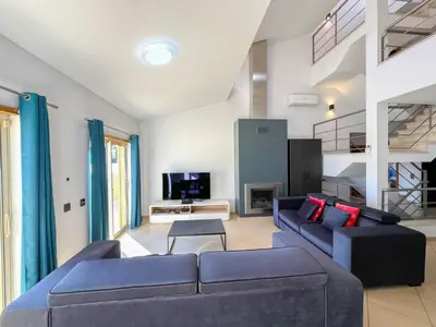 a living room with two blue couches and a tv at Fantastic Villa, Private Pool, BBQ, AC and Wi-Fi in Quarteira