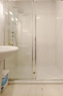 a white bathroom with a shower and a sink at Appartement Albufeira in Albufeira