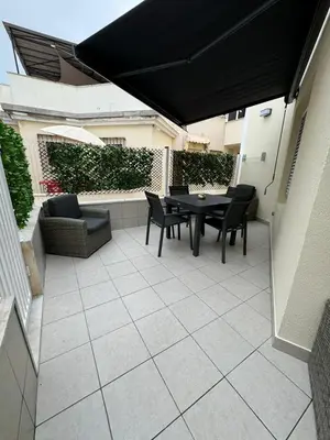 a patio with a table and chairs and a black umbrella at Marina Gemeos - Vilamoura Center by HD Properties in Vilamoura