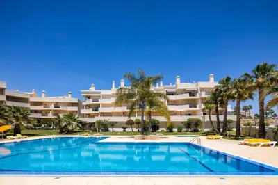 a swimming pool in front of a large building at Stylish 2BR Apartment with Pool Parking & WiFi in Albufeira