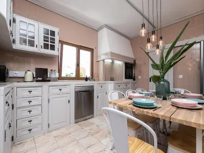 a kitchen with a wooden table and white cabinets at Walk in Hostel Faro Airport in Faro