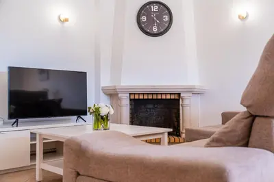 a living room with a fireplace and a clock on the wall at Villa Gil in Albufeira