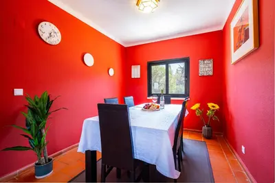a red dining room with a table and a clock at Orange Tree House in Albufeira